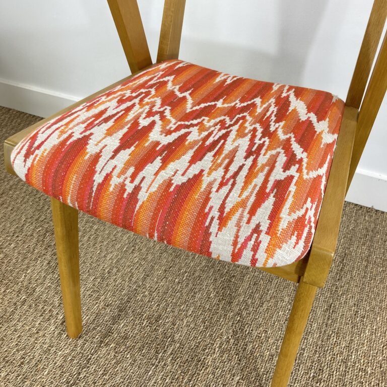 Détail de l'assise d'un fauteuil bridge vintage restauré, tissu orange et rouge