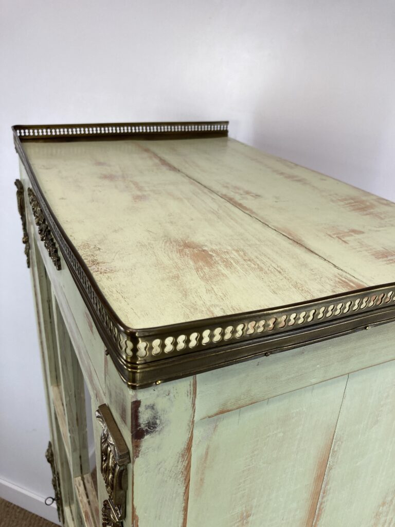 Détail du dessus de l'armoire vitrine ancienne et de sa galerie en laiton