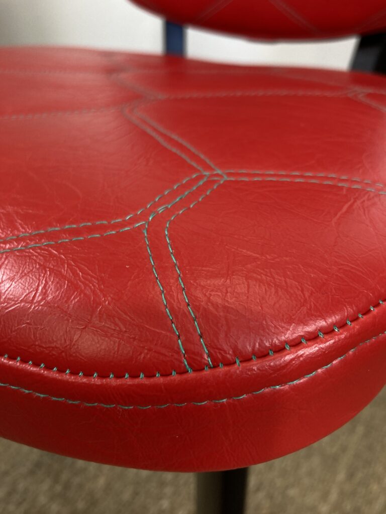 Détail de l'assise en skaï rouge avec surpiqûres vertes