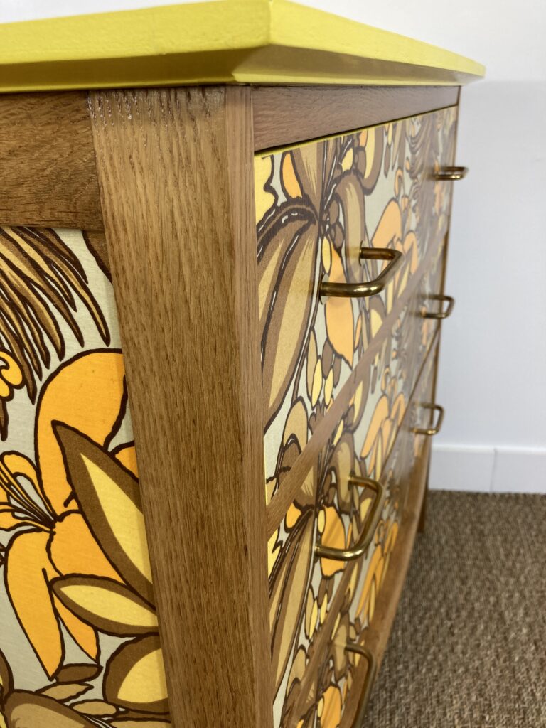Détail de la façade, du tissu floral et des poignées de la commode