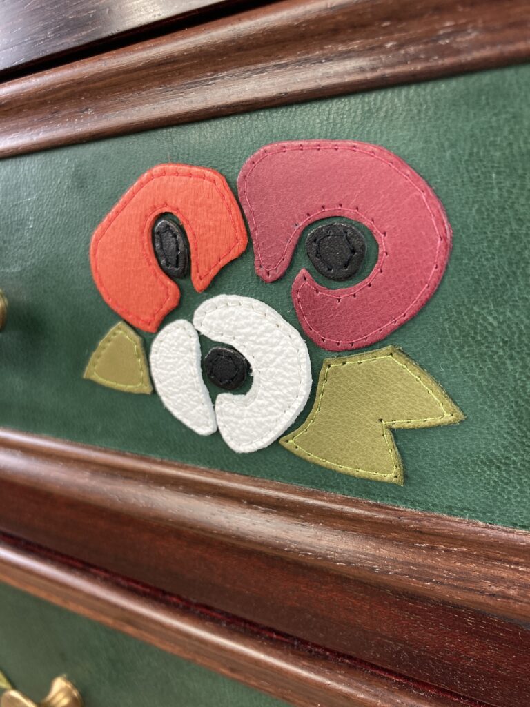 Détail du décor floral en cuir appliqué sur un tiroir