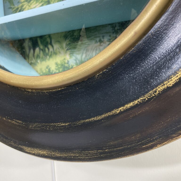 Détail de la porte noire et dorée de la vitrine œil-de-bœuf