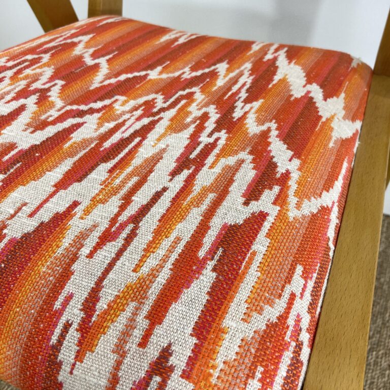 Détail du tissu orange, rouge et écru d'un fauteuil bridge vintage