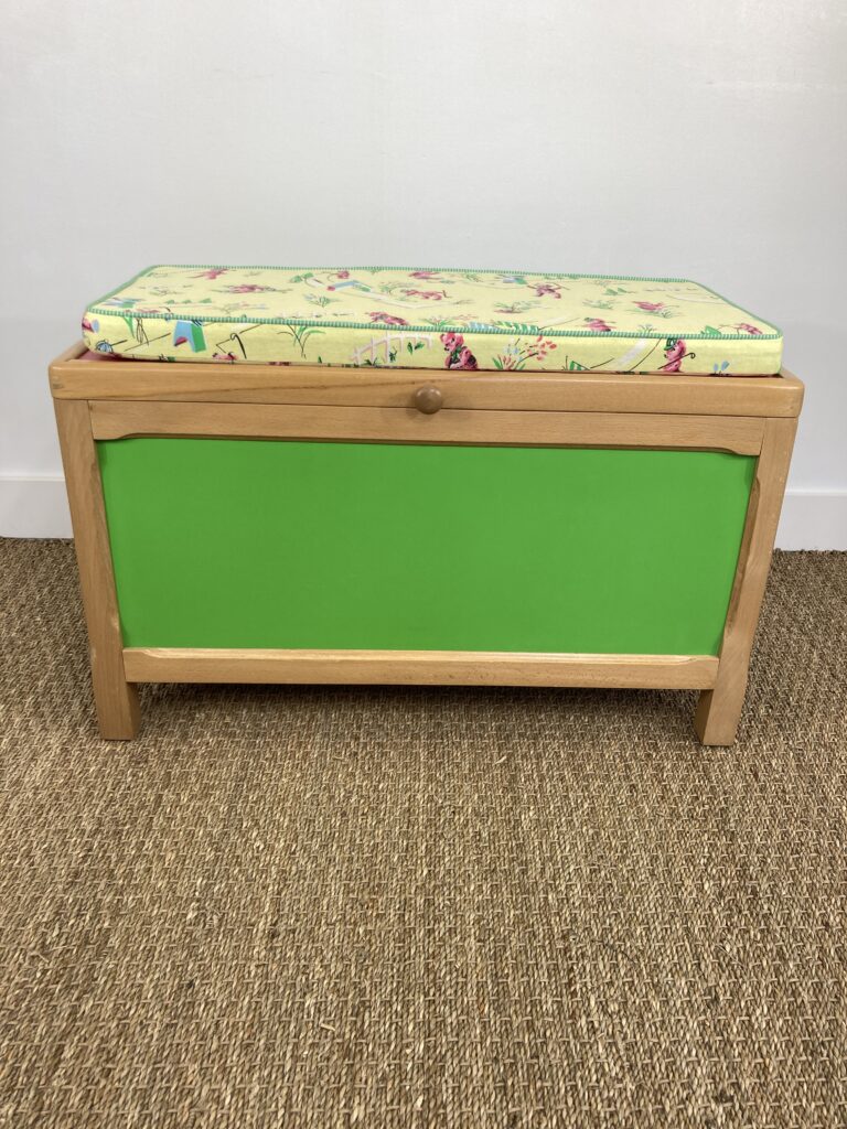 Coffre à jouets en hêtre restauré avec panneaux verts et coussin vintage, vue de face
