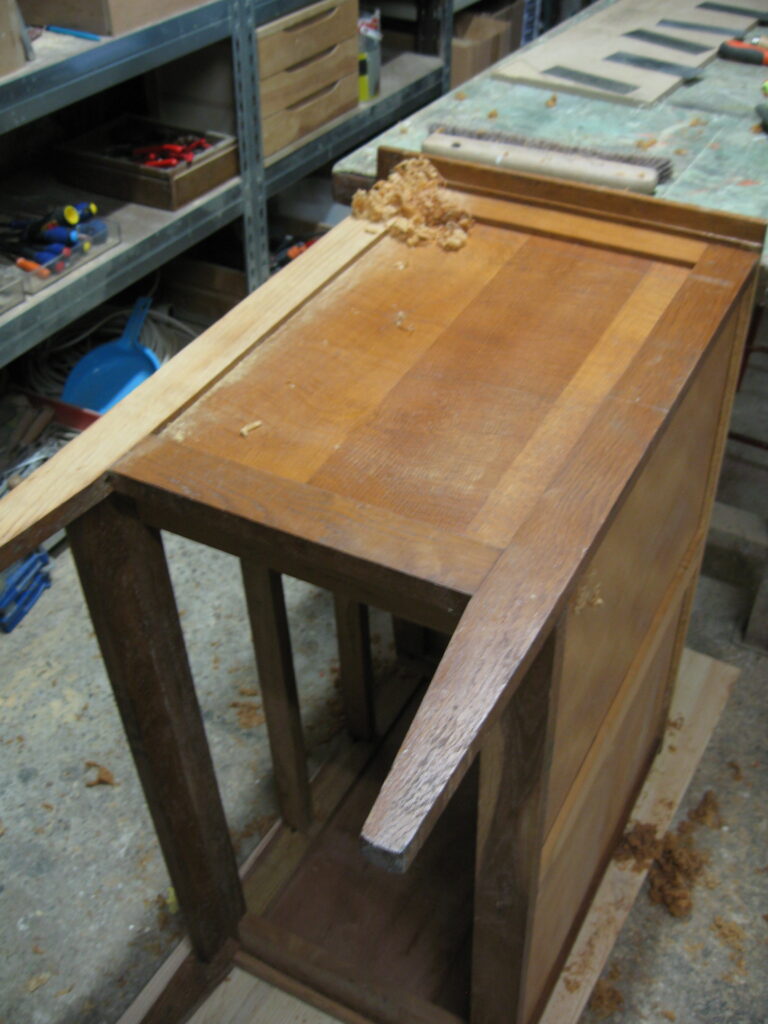 Raclage de l’ancien vernis lors de la restauration de la commode