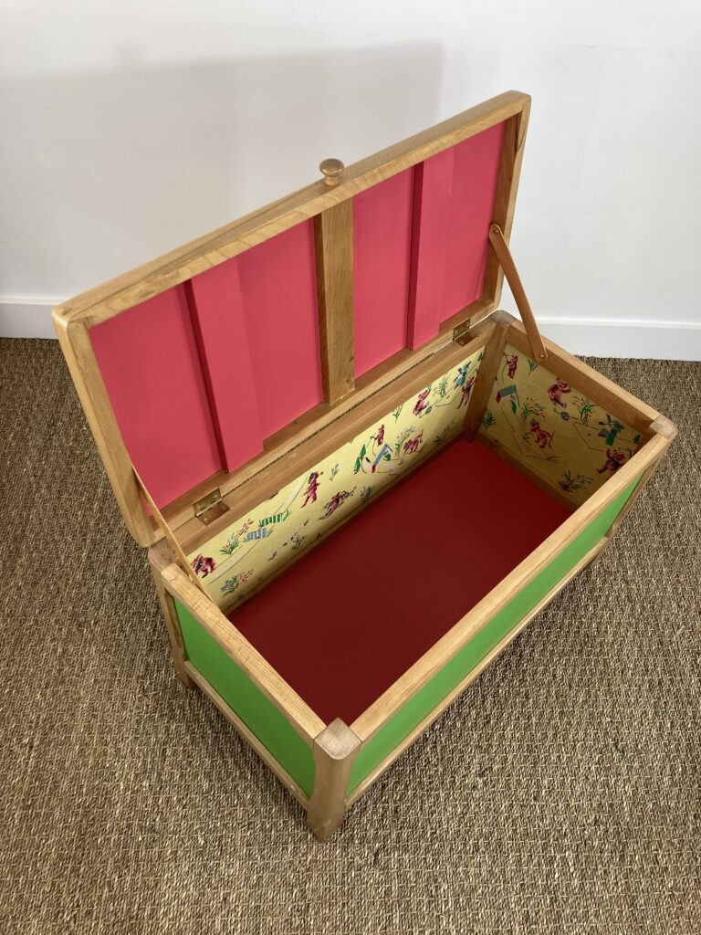 Vue intérieure du coffre à jouets restauré avec tissu vintage et fond coloré