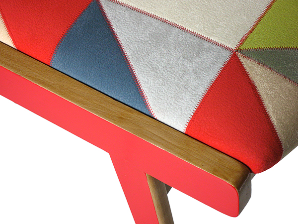 Détail du tissu géométrique et de la finition rouge du fauteuil bridge en hêtre